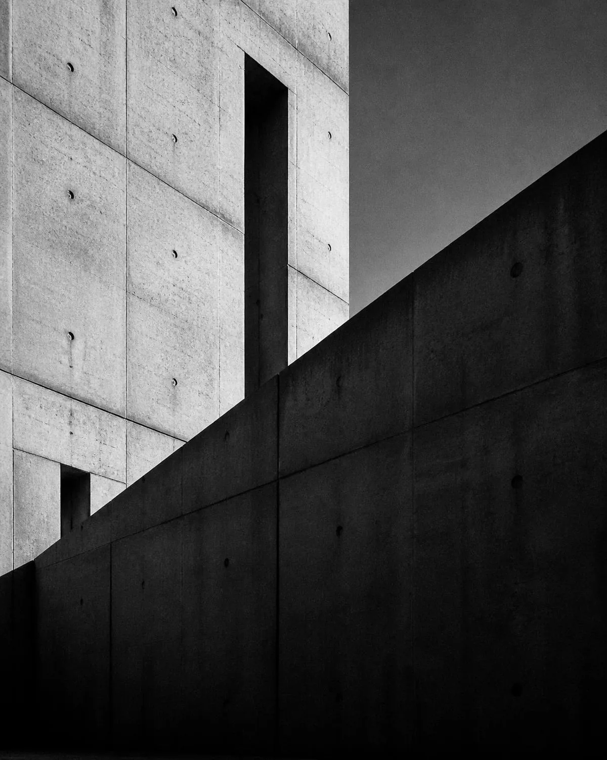 High-contrast concrete facade with a diagonal shadow